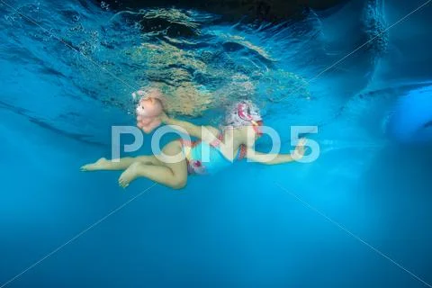 2 years girl with a toy learning to swim underwater in the pool, Stock Photos
