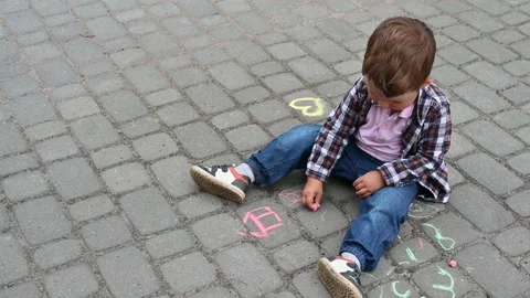 2 years old boy is drawing with colored chalk on the cobblestones Stock Footage 151527037