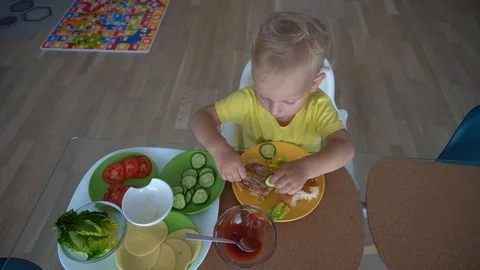 2 years old boy eating hamburger at home. Gimbal stabilizer motion top shot Stock Footage 127956410