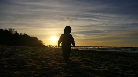 2 years old boy running forward on the sand silhouette outdoors Stock Footage 100290346