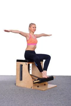 A 20-year-old trainer practices Pilates on an elevator chair, raising her arms Stock-Fotos
