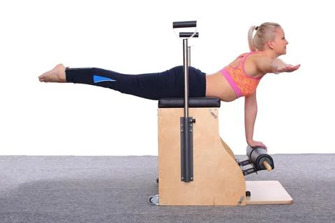 A 20-year-old trainer is practicing Pilates on an elevator chair, lying on her Stock-Fotos