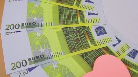200 euro banknotes rotating on a table with multi-colored heart-shaped stickers Vídeo Stock 141314856