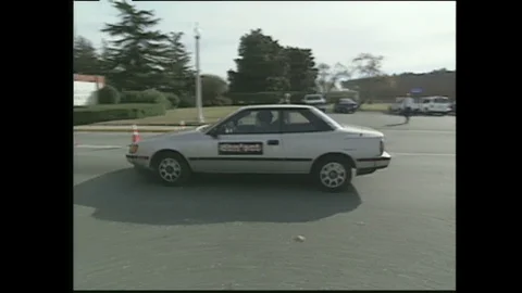 2000s: car passes traffic cones, NASA sign, woman and boy walk inside hangar to Vidéo 128005917