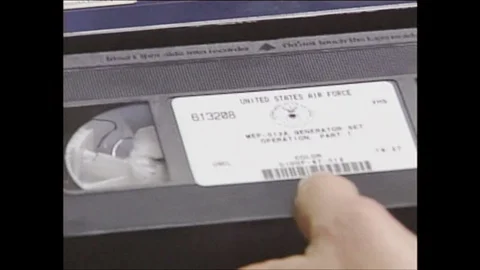 2000s: Hand pushes video tape into VCR.  Man digs with front end loader at Stock Footage 129565932
