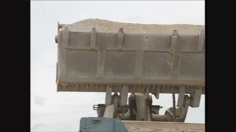 2000s: Man empties dirt into dump truck from front end loader. Stock Footage 129565854