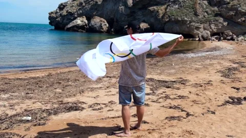 20.05.2021. Sochi. Summer Olympic Games in Tokyo. Man with a flag on the beach Stock Footage 158632798