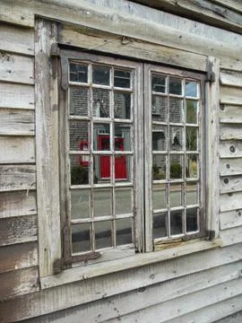 2013-09 - Red door reflecting in an old rustic window Stock Photos