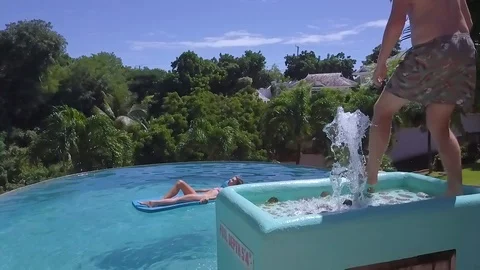2018 - super slow motion shot of a man doing a cannonball dive into a pool and Stock Footage 109555268