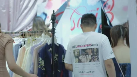 2019 Aug 04, Shanghai. Multiple shoppers browsing garments on a clothing rack Stock Footage 345903967