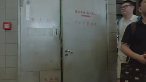 2019 Aug 04, Shanghai. Security guard peeks from staff only door as men walk Stock Footage 345907313