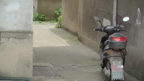 2019 Jun 08, Jiaxing. Dusty electric scooter parked against concrete wall Stock Footage 345406096