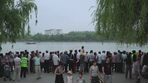 2019 Jun 10, Jiaxing. Crowd watches rowing boats on lakeside promenade Stock Footage 338289256
