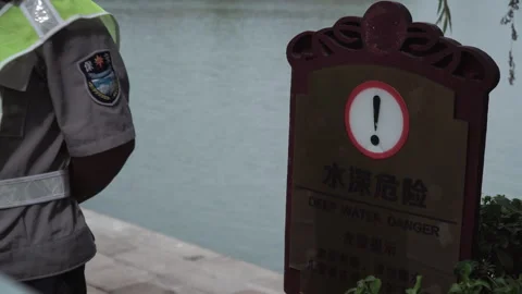 2019 Jun 10, Jiaxing. Guard beside deep water warning sign at waterfront Stock Footage 338281546