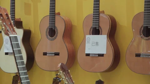 2019 Oct 13, Shanghai. Handcrafted classical acoustic guitars on yellow wall Stock Footage 345924132