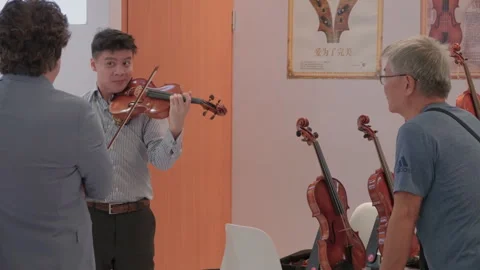 2019 Oct 13, Shanghai. Men examine and play wooden violins Stock Footage 345929013