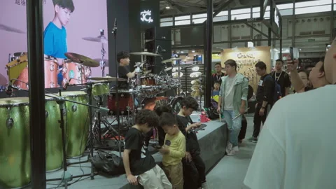 2019 Oct 13, Shanghai. Young boy plays drum kit on indoor exhibition stage Stock Footage 345927825