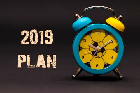 2019 plan written with alarm clock on black paper background Illustrazione stock