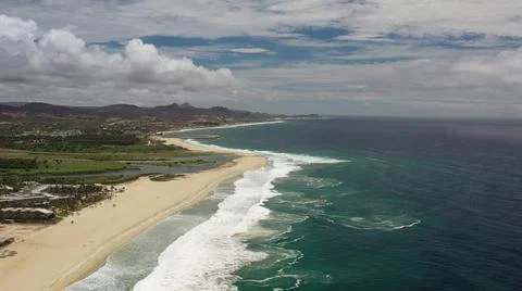 2020:LOS CABOS MEXICO.Ocean Waves Hitting Beach With Plants Covered Dunes Below Stock Photos