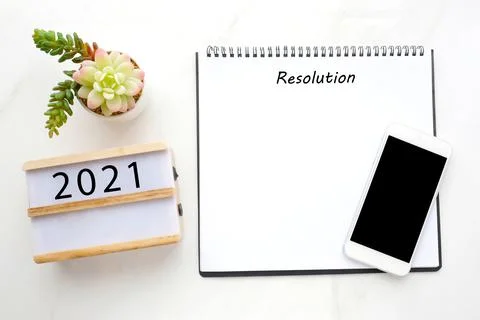 2021 resolution on blank notebook paper, smart phone with blank screen on whi Stock Photos