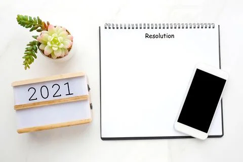 2021 resolution on blank notebook paper, smart phone with blank screen on whi Stock Photos