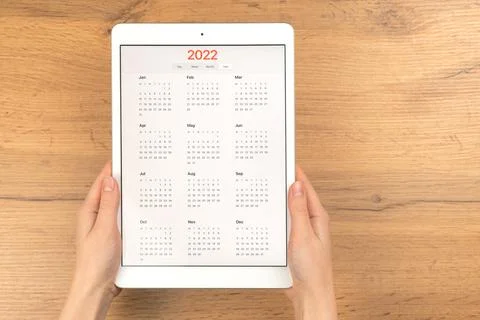 2022 calendar on tablet computer screen. Business wooden table desktop backgr Stock Photos