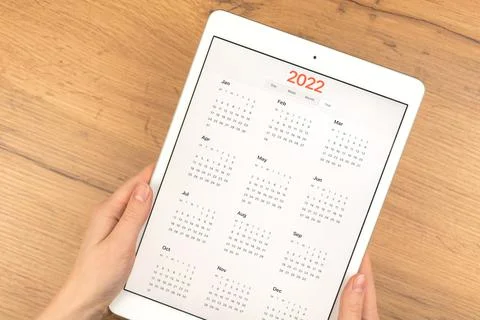 2022 calendar on tablet computer screen. Business wooden table desktop backgr Stock Photos