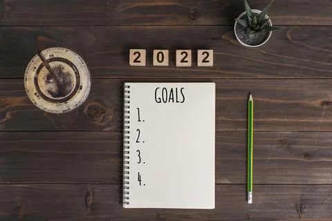 2022 goals text on notepad with coffee cup and pen on wooden desk Stock Photos