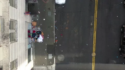 2022 - Overhead view pulling away from a homeless man wrapping his hand in 库存影片 234398987