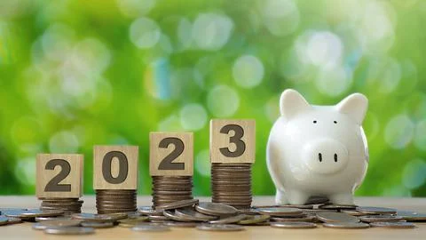 2023 wooden text block on stack of coin and piggy bank with green backgound.. Stock Photos