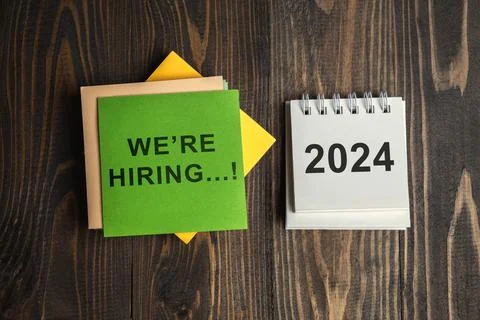 2024 calendar and a stack of note paper with We're Hiring text Stock Photos