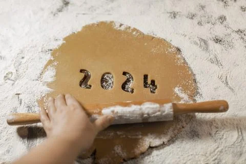 2024 numbers cut from rolled raw cookie dough on flour with woman's hand Stock Photos