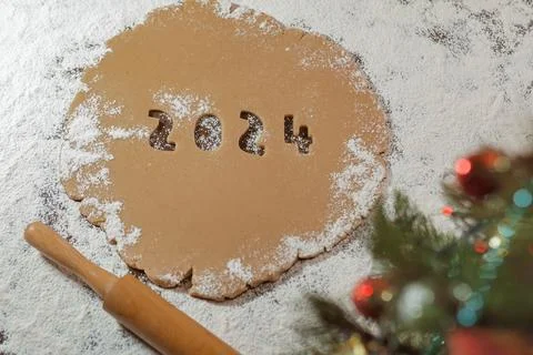 2024 numbers cut from rolled raw cookie dough on flour black table Stock Photos