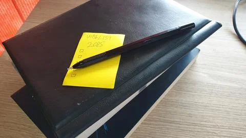 2025 resolution by writing a list using a black pen with a book background Stock Photos