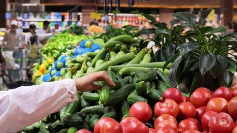2026 Jul 04. Shoppers Select Fresh Cucumbers at Supermarket Produce Aisle 動画素材 339085632