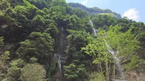 2026 Jul 15, Wulong. Multiple thin cascading waterfalls flow down lush green Stock Footage 340537547