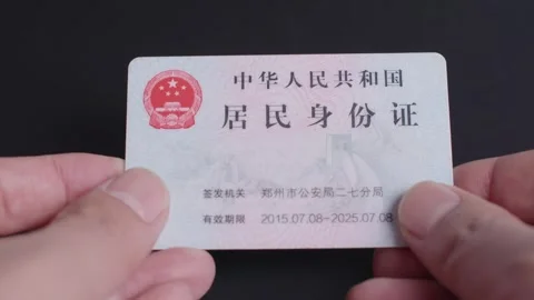 2026 Jun 09, China. Hands Holding Chinese Resident Identity Card Against Dark Stockbeeldmateriaal 336548413