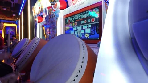 2026 Jun 29, Shanghai. Players drum taiko arcade game in neon-lit indoor arcade Stock Footage 337880248