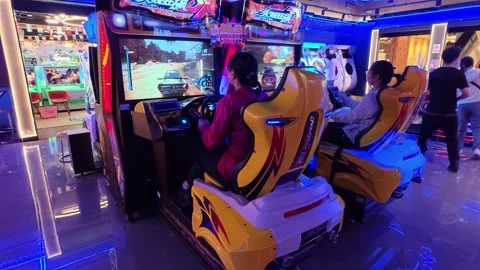 2026 Jun 29, Shanghai. Two young women from behind play racing arcade game Stock Footage 337880104
