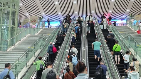 2026 Jun 30, Shanghai. Diverse passengers ascending parallel escalators Stock Footage 338232115