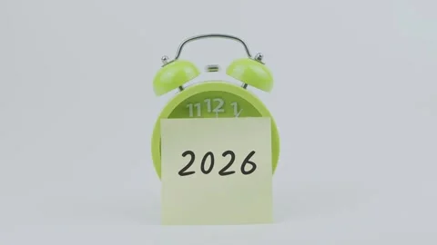 2026 word on sticky note in front of green clock and ringing on white Stock Footage 313973763