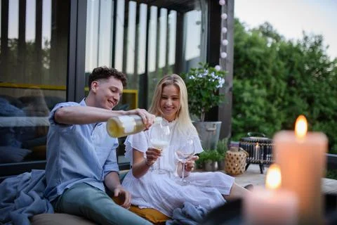 A young couple clinking with wine outdoors, weekend away in tiny house in countryside, sustainable living. xkwx love, wine, couple, woman, man, outdoor, happy, terrace, romance, romantic, together, young, drink, glass, person, smiling, caucasian, celebration, lifestyle, garden, party, relationship, two, alcohol, cheerful, vacation, tourism, closeness, date, honeymoon, newlyweds, lover, positive, togetherness, drinking, champagne, evening, holding, tiny house, holiday, nature, off beat, relax, meditation, digital detox, candle, hygge, travel, weekend away