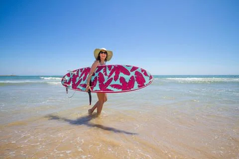 A Hispanic woman wearing a swim wear while holding a surf board on the beach xkwx attractive, beach, coast, female, girl, happy, hispanic, holiday, leisure, lifestyle, ocean, people, person, pretty, sand, sea, summer, surf, swim, vacation, voard, water, wear, woman, young