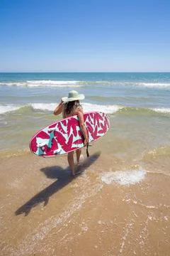 A Hispanic woman wearing swimwear while holding a surfboard on the beach xkwx active, activity, Am, beach, beautiful, beauty, bikini, body, coast, Continente, Estados Unidos de Am, fashion, female, fun, girl, happy, Hawaii, holding, holiday, leisure, lifestyle, nature, ocean, outdoors, paradise, people, person, recreation, relax, resort, retro, rica, rica del Norte, sand, sea, shore, sport, style, summer, sun
