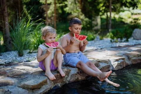 Little chidren sitting near a lake and eating watermelon on hot sunny day during summer vacation. xkwx happiness, watermelon, fruit, kid, happy, green, nature, red, food, fun, picnic, healthy, outdoor, joy, health, juicy, eat, girl, childhood, slice, boy, nutrition, cute, sweet, smile, little, eating, cheerful, snack, summertime, caucasian, meal, enjoy, outside, melon, garden, water, delicious, friend, refreshment, holiday, brother, sister, freshness, warm, preschool, siblings