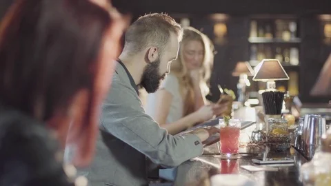 20s bearded guy people is drink cocktail sitting bar counter with menu Stock Footage 75239095