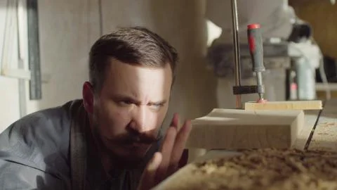 20s bearded woodworker using brashing machine tool and checking quality of work Stock Photos