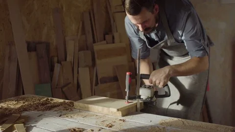 20s bearded woodworker works with brashing machine at sunny day in workshop Stock Footage