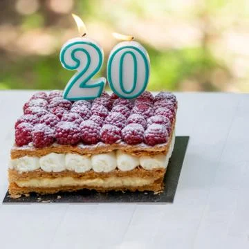 20th birthday raspberry cake with burning candles Stock Photos