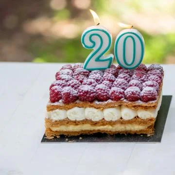 20th birthday raspberry cake with burning candles Stock Photos